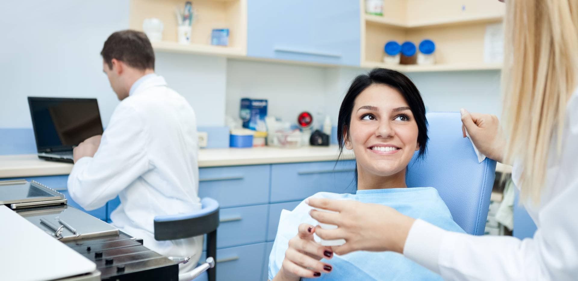 Úsměvavá pacientka mluvící se zubařkou v ordinaci.